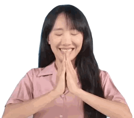 a woman in a pink shirt is smiling with her hands folded in front of her face