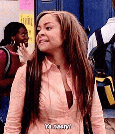 A Woman In A Pink Shirt Is Standing In Front Of A Blue Door . GIF