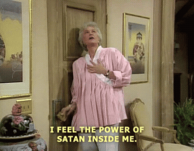 A Woman In A Pink Shirt Is Standing In Front Of A Door Saying I Feel The Power Of Satan Inside Me . GIF