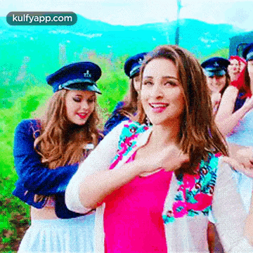 A Woman In A Pink Shirt Is Standing In Front Of A Group Of People Wearing Hats . GIF