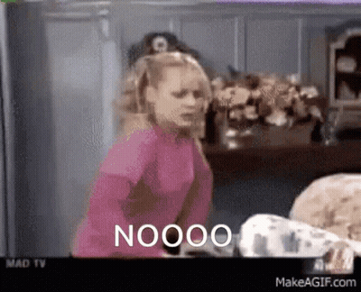 A Woman In A Pink Shirt Is Standing In Front Of A Tv Screen That Says Nooo GIF