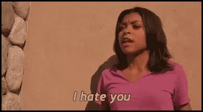 A Woman In A Pink Shirt Is Standing In Front Of A Wall And Saying `` I Hate You '' . GIF