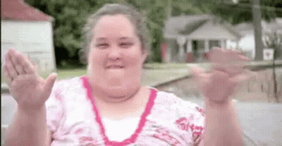 A Woman In A Pink Shirt Is Waving Her Hands In The Air . GIF