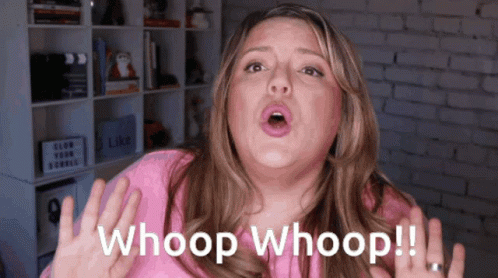 A Woman In A Pink Shirt Says Whoop Whoop In Front Of A Brick Wall GIF