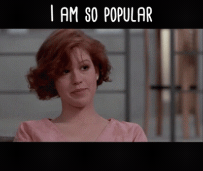 A Woman In A Pink Shirt With The Words " I Am So Popular " Below Her GIF