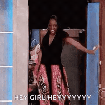 A Woman In A Pink Skirt Is Standing In A Doorway With Her Arms Outstretched . GIF