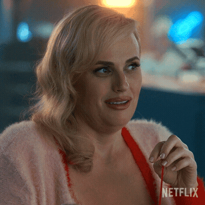A Woman In A Pink Sweater Is Holding A Red Ribbon With Netflix Written On The Bottom Right GIF