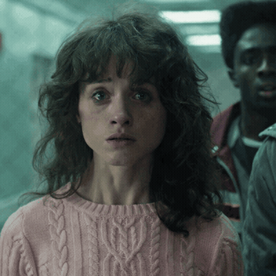 A Woman In A Pink Sweater Is Looking At The Camera GIF
