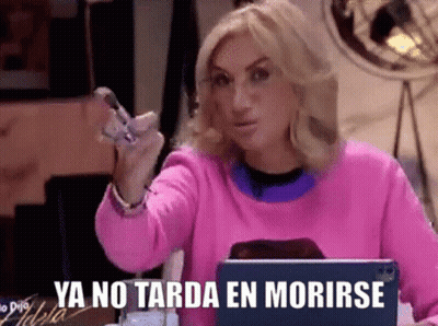 A Woman In A Pink Sweater Is Sitting In Front Of A Laptop And Holding A Cell Phone In Her Hand . GIF