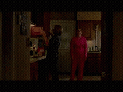 A Woman In A Pink Sweater Is Standing In A Kitchen GIF