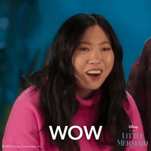 A Woman In A Pink Sweater Says Wow In Front Of A Blue Background . GIF