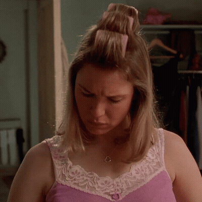 A Woman In A Pink Tank Top And White Lace Trim Looks Down GIF