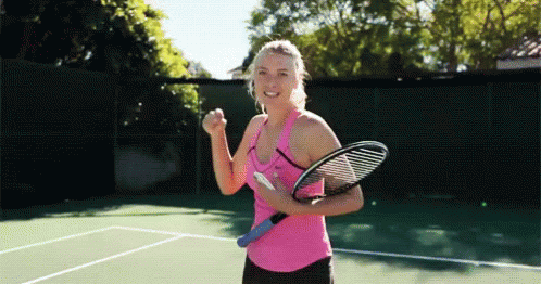 A Woman In A Pink Tank Top Is Holding A Tennis Racket On A Tennis Court . GIF