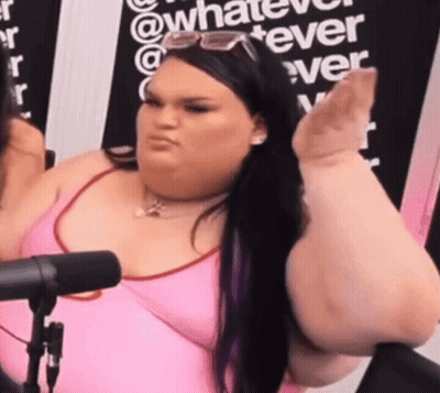 A Woman In A Pink Tank Top Is Sitting In Front Of A Microphone Making A Funny Face . GIF