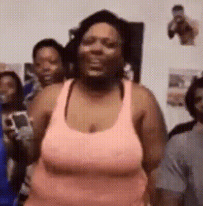 A Woman In A Pink Tank Top Is Standing In Front Of A Group Of People And Smiling . GIF