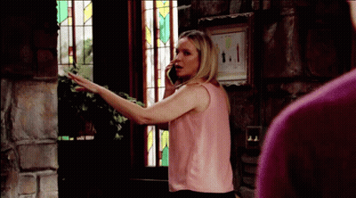 A Woman In A Pink Tank Top Is Talking On A Cell Phone GIF