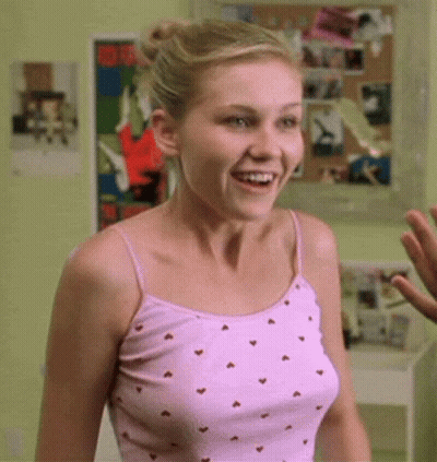 A Woman In A Pink Tank Top With Hearts On It Is Smiling GIF