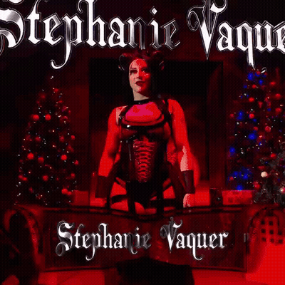 A Woman In A Pink Top And Black Corset Is Standing In Front Of A Red Background With The Name Stephanie Vaquer On It . GIF
