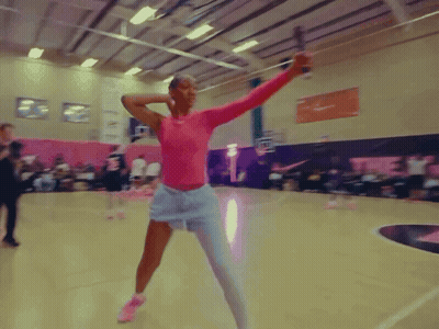 A Woman In A Pink Top And White Shorts Is Holding A Sword GIF