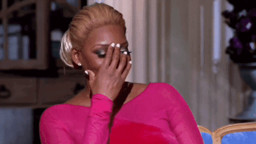 A Woman In A Pink Top Is Covering Her Face With Her Hand . GIF