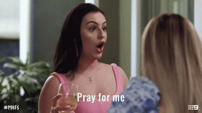 A Woman In A Pink Top Is Holding A Wine Glass And Says Pray For Me GIF