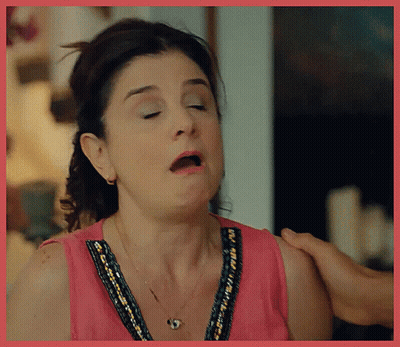 A Woman In A Pink Top Is Making A Funny Face With Her Mouth Open GIF