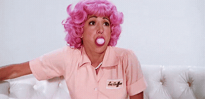 A Woman In A Pink Wig Blowing A Bubble With Her Mouth GIF
