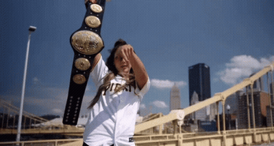 A Woman In A Pittsburgh Shirt Is Holding A Wrestling Belt Over Her Head GIF