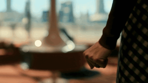 A Woman In A Plaid Dress Holds Her Fist Up In A Blurry Photo GIF