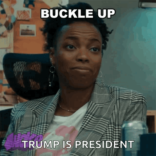 A Woman In A Plaid Jacket Is Sitting In A Chair With A Meme That Says " Buckle Up Trump Is President " GIF