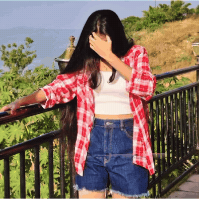 A Woman In A Plaid Shirt And Shorts Covering Her Face GIF