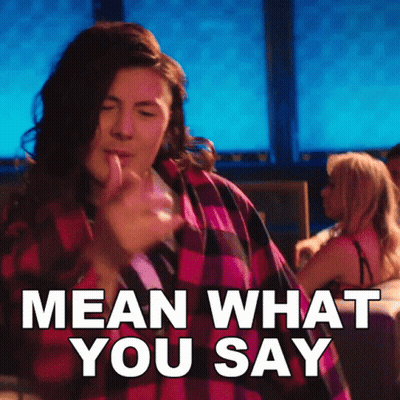 A Woman In A Plaid Shirt Is Dancing And Says Mean What You Say GIF