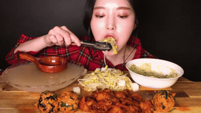 A Woman In A Plaid Shirt Is Eating A Meal With Tongs GIF