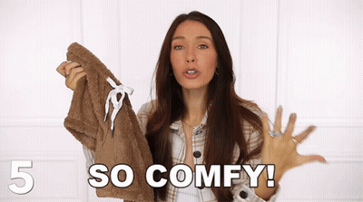 A Woman In A Plaid Shirt Is Holding A Brown Jacket And Saying So Comfy GIF