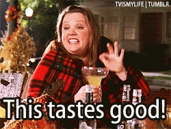 A Woman In A Plaid Shirt Is Holding A Martini Glass And Says This Tastes Good GIF