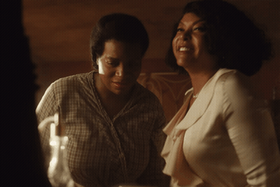 A Woman In A Plaid Shirt Is Laughing With Another Woman In A White Shirt GIF