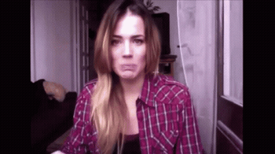 A Woman In A Plaid Shirt Is Making A Face . GIF