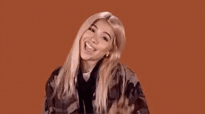 A Woman In A Plaid Shirt Is Making A Funny Face And Waving Her Hand In The Air . GIF