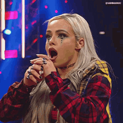 A Woman In A Plaid Shirt Is Making A Funny Face With Her Mouth Open . GIF