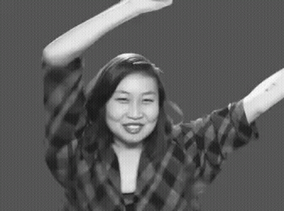 A Woman In A Plaid Shirt Is Raising Her Arms In The Air . GIF