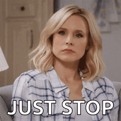 A Woman In A Plaid Shirt Is Sitting On A Couch With The Words Just Stop Below Her GIF