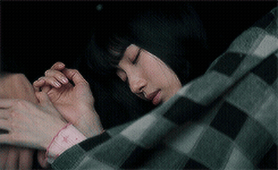 A Woman In A Plaid Shirt Is Sleeping Under A Blanket GIF