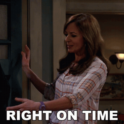 A Woman In A Plaid Shirt Is Standing In Front Of A Door With The Words Right On Time Behind Her GIF