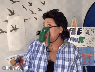 A Woman In A Plaid Shirt Is Standing In Front Of A Sign That Says Free Swank GIF