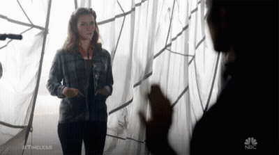 A Woman In A Plaid Shirt Is Standing Next To A Man In A Black Shirt With Nbc Written On The Bottom Right GIF