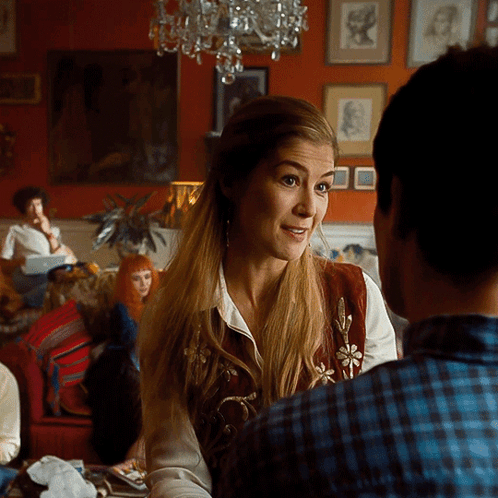 A Woman In A Plaid Shirt Is Talking To A Man In A Living Room GIF