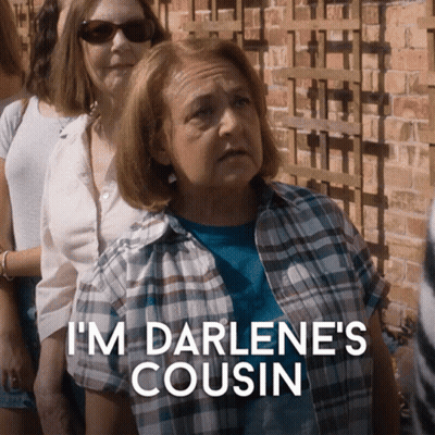 A Woman In A Plaid Shirt Says " I 'M Darlene 'S Cousin " In Front Of A Group Of People GIF
