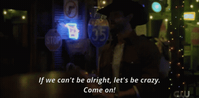 A Woman In A Plaid Shirt Stands In Front Of A Bar With A Neon Sign That Says Beer GIF