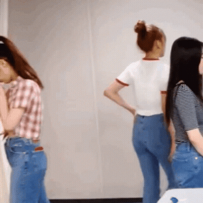 A Woman In A Plaid Shirt Stands Next To Two Other Women In Blue Jeans GIF