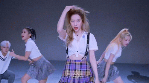 A Woman In A Plaid Skirt And Suspenders Is Dancing With A Group Of Dancers . GIF